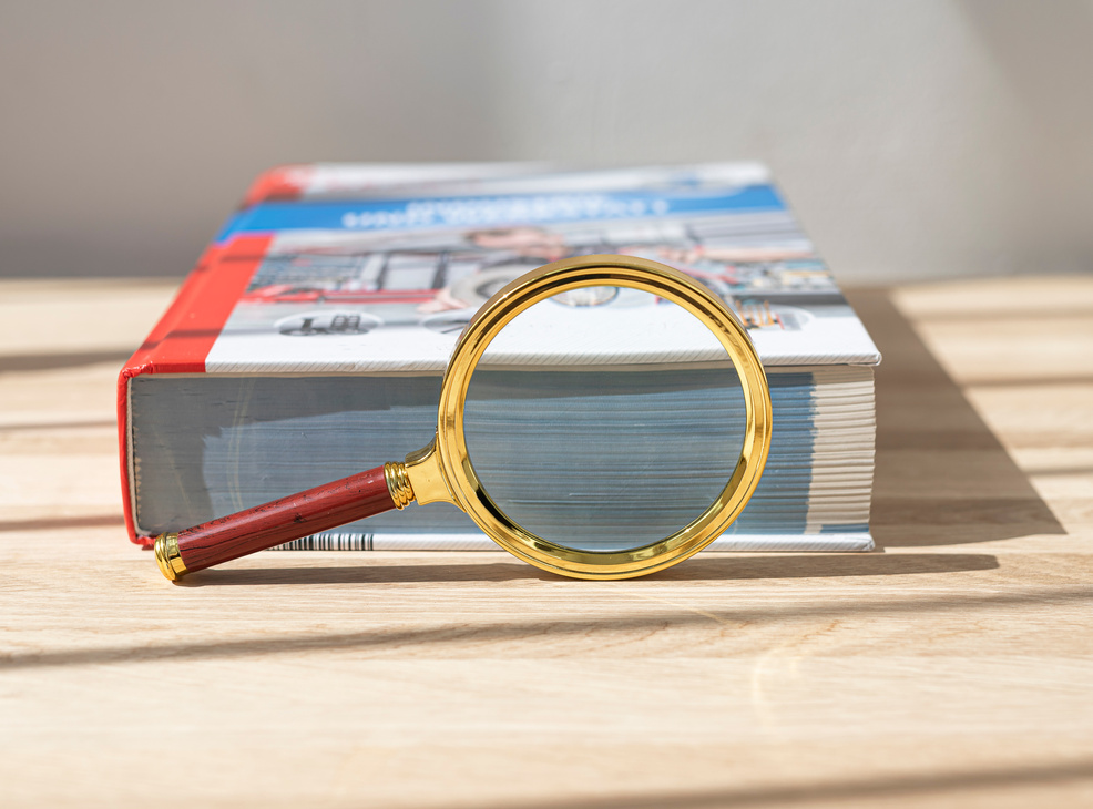 Open Technical Book for Study Physics with Magnifying Glass and Ruler